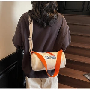 Vue arrière du sac tonneau en toile avec bandoulière orange sur un mannequin