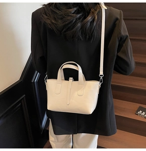 Close-up of a glossy beige trapezoid tote bag with dual handles and detachable strap