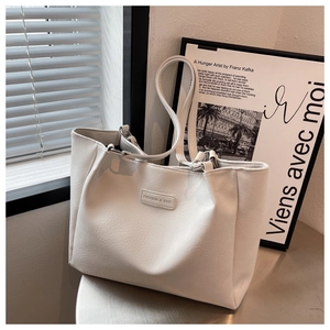 Detail of lychee textured leather tote bag with FASHION & BAG metallic logo plaque