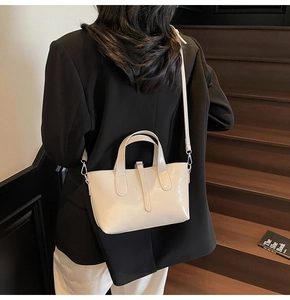 Model wearing a premium cream glossy crossbody bag made of shiny patent leather material