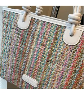 Close-up of vibrant multi-color woven texture and white leather handle on a summer tote