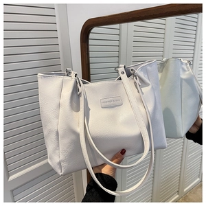 Close-up of white tote bag showing natural pebble leather texture and fashion brand tag