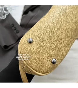 Makro-Detail der cremefarbenen Beuteltasche mit silbernen Nieten und Lychee-Leder