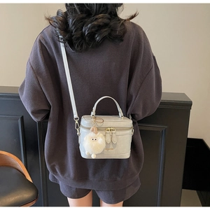 Borsa a tracolla in pelle grigio chiaro con ciondolo peluche indossata da modella