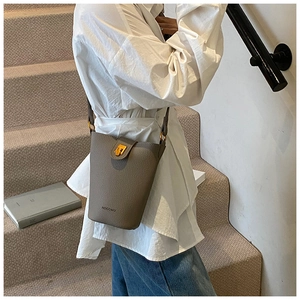 Detailansicht graue Beuteltasche mit Litschi-Textur und Goldschnalle an Model
