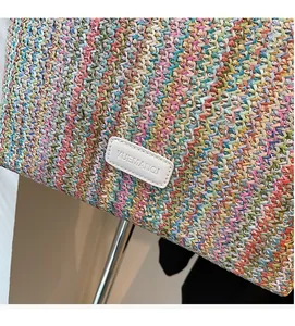 Close-up of colorful woven straw tote bag featuring a white leather logo patch