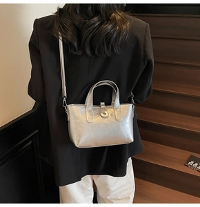 Silver metallic tote bag styled as a crossbody on model during indoor commute