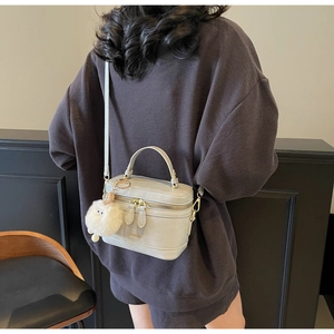 Vue détaillée du sac bandoulière gris avec poignée et pompon blanc décoratif en peluche