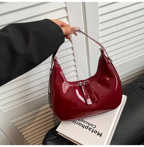 Détail du sac à bandoulière en cuir verni bordeaux avec finition brillante et zip