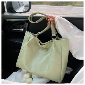 Close-up of light green tote bag showing pebbled leather texture and fashion label