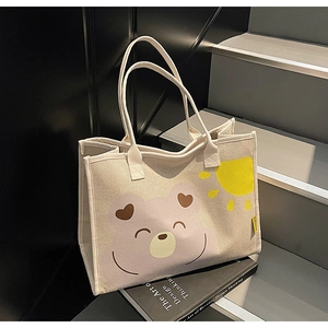 Détail d'un sac cabas en toile avec ours rose sur des marches minimalistes