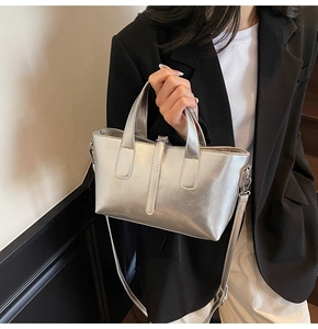 Detail of silver tote bag with textured finish, detachable strap and top handle