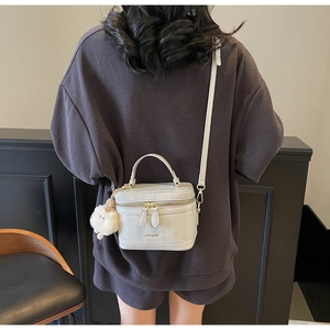 Model wearing a light grey mini box bag with a cute sheep charm and gold zipper details