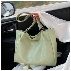 Detail view of the light green faux leather tote bag showing texture and silver hardware