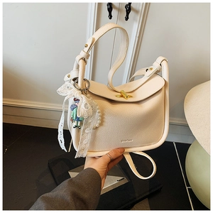 Detail of cream crossbody bag with lychee texture leather and a gold turn-lock closure