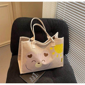 Détail d'un sac cabas en toile avec motif d'ours sur un fauteuil en velours