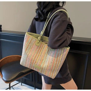 Detail of colorful woven tote bag featuring olive green knotted leather handles and logo