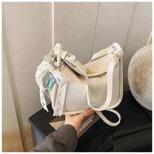 Detail of off-white crossbody bag featuring a lace bow, pearl chain and doll charm