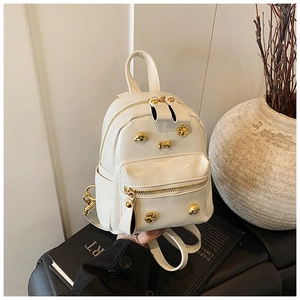 Close-up of cream PU leather backpack with gold dog-themed metal charms and rivets