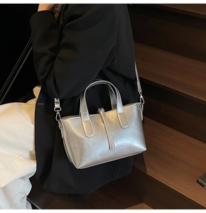 Silver metallic bucket bag with pleated texture shown as a stylish crossbody on a model