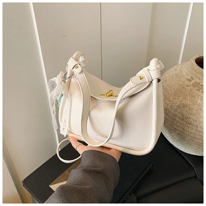 Detail of off-white lychee texture leather bucket bag with gold buckles and lace ribbon