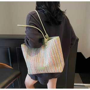 Close-up of rainbow striped woven tote bag with green leather handles and knot details