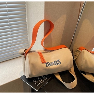 Détail du sac cylindrique en toile avec broderie 1985 et bandoulière orange vif