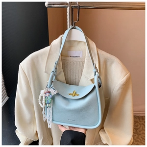 Detail of light blue litchi pattern leather bag with pearls, lace, and a cute doll charm