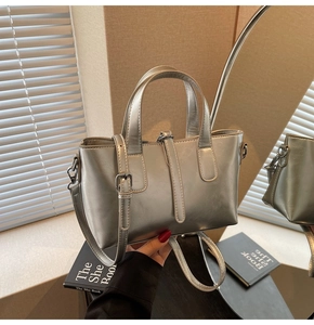 Close-up of silver metallic patent leather handbag with mirror-like finish and handle