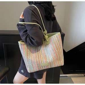 Detail of colorful woven tote bag showing vertical stripes and light green leather handles