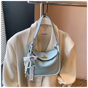 Detail of light blue lychee pattern leather bag with lace bow and cartoon charm decorations