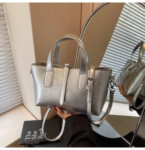 Close-up of metallic silver handbag featuring fine stitching and buckle strap detail
