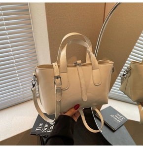 Detail of cream white glossy leather tote bag with silver buckle and thin strap
