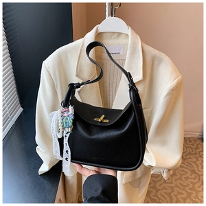 Detail of black pebbled leather hobo bag featuring gold twist lock and a cute charm
