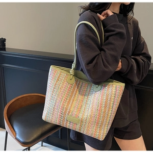 Detail of colorful striped woven tote bag with green leather knotted strap and logo