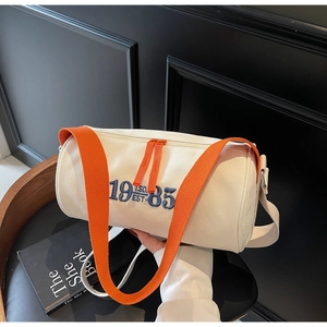 Détail de la broderie 1985 et de la bandoulière orange sur le sac cylindre en toile