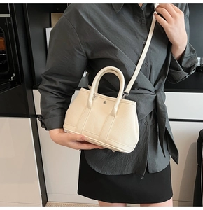 Detail der cremefarbenen Ledertasche mit Litschi-Textur und Metall-Hardware-Schnalle