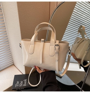 Detail of creamy white leather handbag with silver hardware and chic belt buckle accent