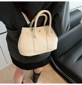 Detailaufnahme der cremeweißen Leder-Beuteltasche mit silberner Metallschnalle und Narbung