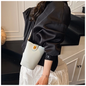 Nahaufnahme der hellgrauen Leder-Eimertasche mit Goldverschluss und Markenlogo