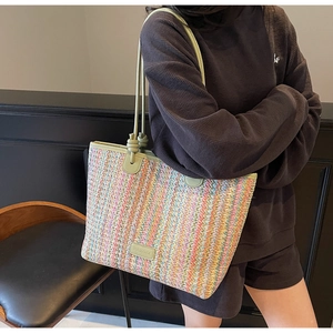 Detail of colorful striped woven tote bag with light green leather strap and logo