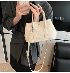 Nahaufnahme einer beigen Handtasche aus Leder mit Litschi-Maserung und Silber-Schnalle