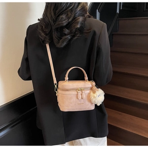 Mini sac boîte rose avec breloque mouton en peluche porté par un mannequin en blazer