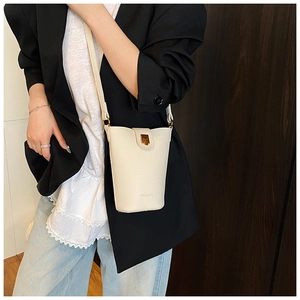 Detail der cremeweißen Beuteltasche mit Lychee-Struktur und goldener Schließe am Model