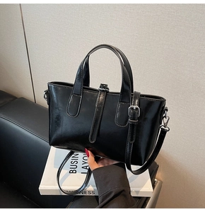 Detail of glossy black leather handbag with silver buckle and adjustable shoulder strap