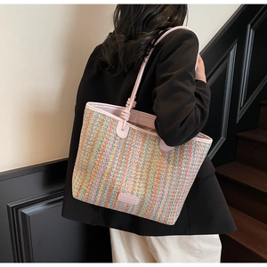 Detail of colorful woven tote bag featuring slim pink straps and a leather brand label