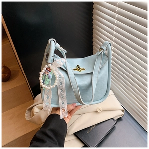 Close-up of light blue pebble leather tote bag with gold twist lock and pearl doll charm