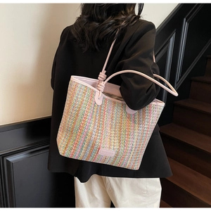 Detail of colorful striped woven tote bag featuring pink shoulder straps and leather logo