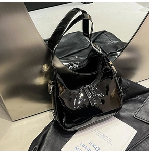 Détail d'un sac en cuir verni noir avec finition brillante et ferrures métalliques