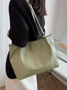 Green leather tote bag with large capacity shown from a side view on a model